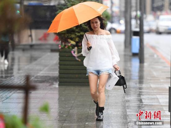 资料图：台风中市民打伞出行。张瑶 摄
